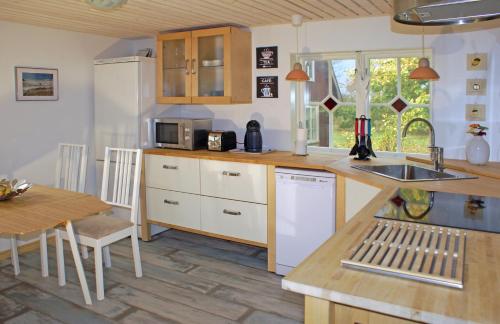 uma cozinha com armários brancos, uma mesa e um lavatório em Haus Fjäril em Laxeby
