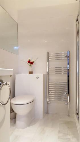 a bathroom with a toilet with a flower on top of it at River Nene Cottages in Water Newton