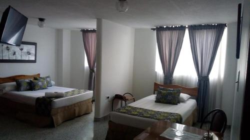 a bedroom with two beds and a couch and a window at Hotel Mirador Santana in Anserma