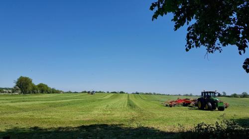 a tractor is parked in a field with a field at River Nene Cottages in Water Newton