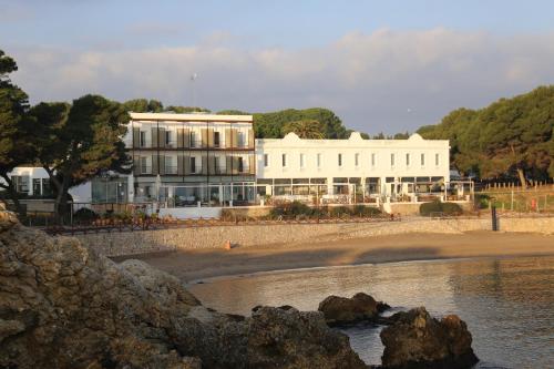 a large white building on the beach near the water at Hostal Spa Empúries in L'Escala