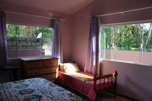 1 dormitorio con 2 camas, vestidor y ventana en Casa do sossego p/até 9 pessoas, en Garopaba