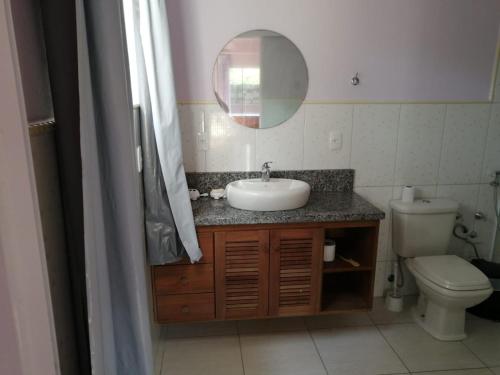Un baño con lavabo, inodoro y espejo. en Casa do sossego p/até 9 pessoas, en Garopaba