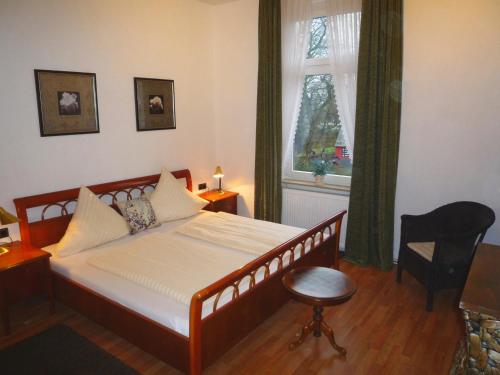 a bedroom with a bed and a chair and a window at Hotel Alt-Lennep in Remscheid