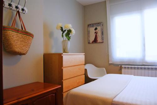 Un dormitorio con una cama y una mesa con un jarrón de flores en Panier en Osier · Panier en Osier · Charming apartment w/private terrace 2min from sea en Vilassar de Mar