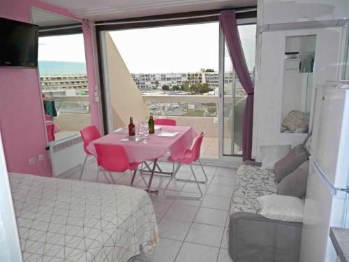Cette chambre dispose d'une table avec des chaises roses et d'un balcon. dans l'établissement studio naturiste, au Cap d'Agde