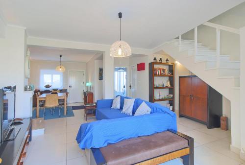 a living room with a blue couch and a staircase at Pool & Tennis Beach House in Praia da Barra