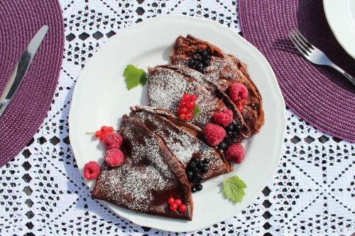 a plate of chocolate pancakes with berries on a table at Dom Malowany in Wetlina