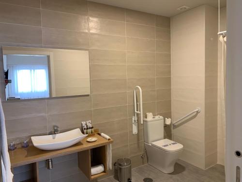 a bathroom with a toilet and a sink and a mirror at Hotel Celanova in Celanova