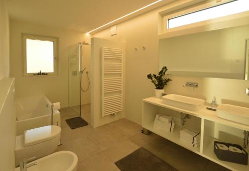 ein Badezimmer mit einem WC, einem Waschbecken und einem Spiegel in der Unterkunft Family Apartment Julia in Tramin an der Weinstraße