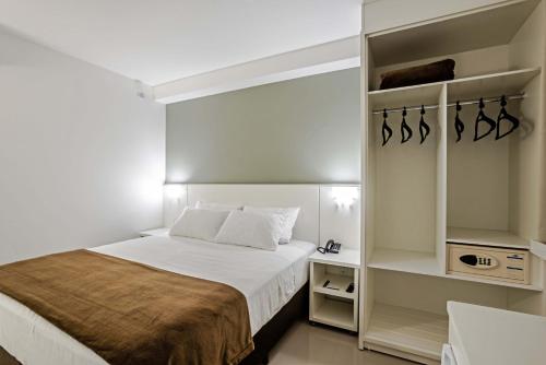 a small bedroom with a bed and shelves at Slim Curitiba João Bettega in Curitiba