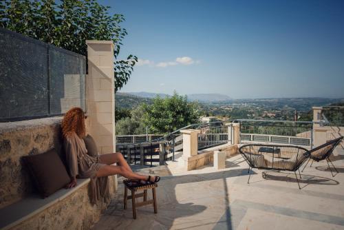 a woman sitting on a wall looking at the view at Prinus Country Retreat Apokoronas, heated pool, 13km from the sea in Embrósneros