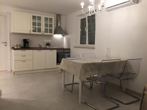 a white kitchen with a table and chairs in it at Fig Tree in Povlja
