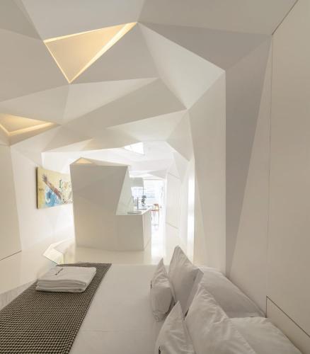 a white room with a bed and a geometric ceiling at LeBlanche in Porto