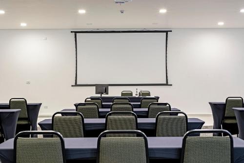 a conference room with chairs and a projection screen at Slim Curitiba João Bettega in Curitiba