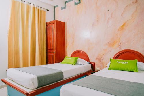 - une chambre avec 2 lits et des oreillers verts dans l'établissement Ayenda 1614 Playa y Mar, à Santa Marta