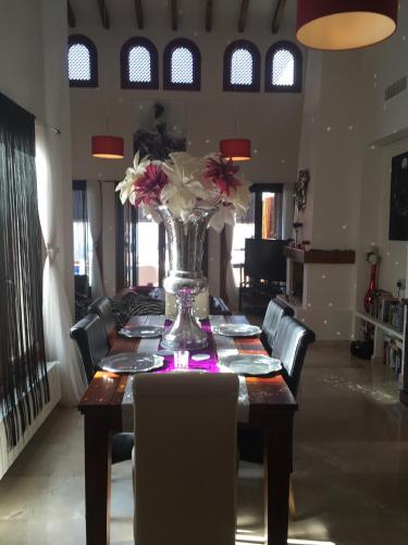 una mesa de comedor con un jarrón de flores. en Casa Catherina Joan - El Valle Golf Resort, en Baños y Mendigo