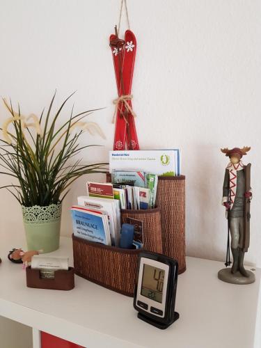 une table avec une horloge, des livres et une statue dans l'établissement Apartment Kleiner Heinrich, à Braunlage