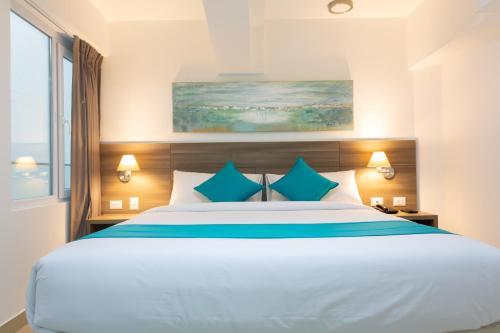 a bedroom with a large white bed with blue pillows at Howard Johnson by Wyndham Lima Miraflores Art House in Lima