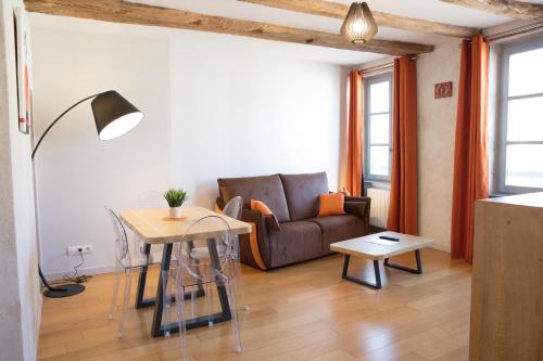 a living room with a couch and a table at Appartement A-Mi-Chemin - Centre-ville de Tournus in Tournus