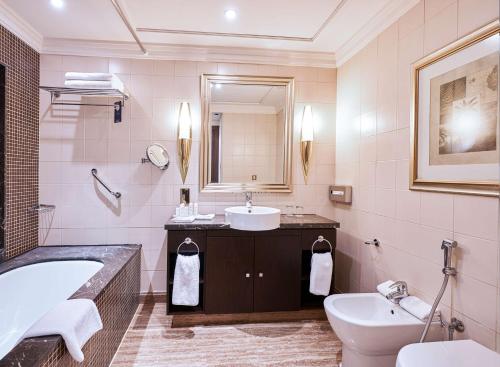 a bathroom with a sink and a tub and a toilet at The Diplomat Radisson Blu Hotel Residence & Spa in Manama