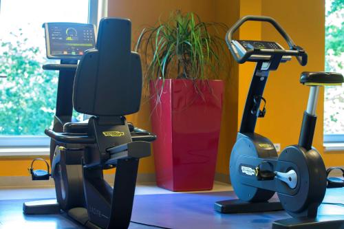 a gym with two exercise bikes next to a plant at Park Inn by Radisson Frankfurt Airport in Frankfurt