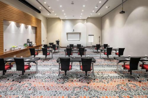 a conference room with tables and chairs and a projection screen at Radisson Blu Resort Jizan in Jazan