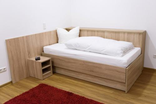 a bed with a wooden headboard and a red rug at Ferienwohnung am Westerturm in Duderstadt