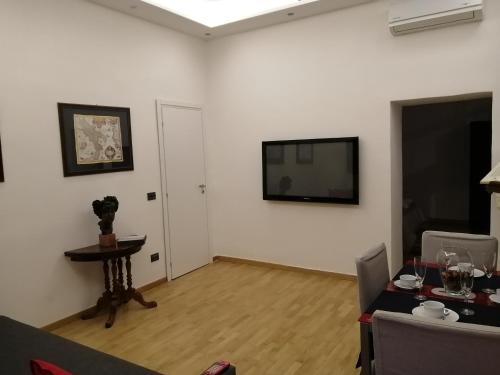 ein Wohnzimmer mit einem Tisch und einem TV an der Wand in der Unterkunft La dimora dei borbone in Neapel