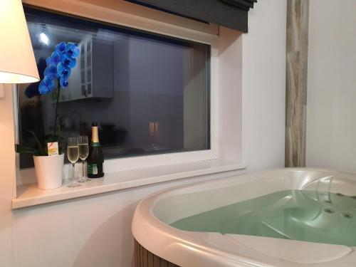 a bath tub in a bathroom with a window at Apartamentai su Jacuzzi in Panevėžys