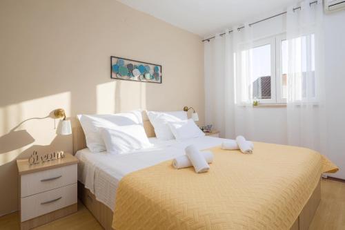 a white bedroom with two beds with towels on them at Lavica Seaside Apartments, Podstrana in Podstrana