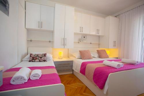 two beds in a room with white cabinets at VILLA MILENKA - Apartmani Gorana in Tučepi