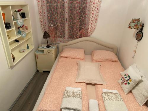 a small bedroom with a bed with pink sheets at Apartments Borove Noci in Vrdnik