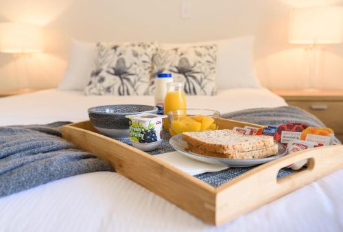 uma bandeja de comida de pequeno-almoço numa cama em Apex Motorlodge em Nelson