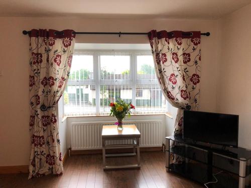 a living room with curtains and a table in front of a window at Glendona Lodge in Glenavy