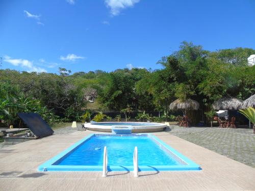 a blue swimming pool with a boat in the background at Hostal Villas Mexico in San Juan del Sur