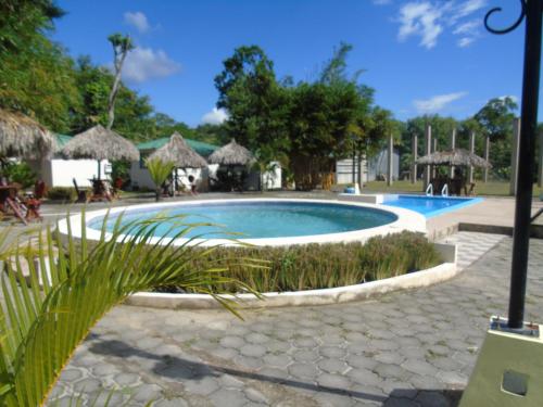 a swimming pool in a resort with grass at Hostal Villas Mexico in San Juan del Sur
