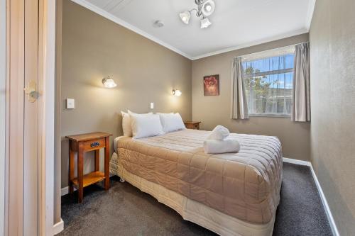 a small bedroom with a bed and a window at Tower Lodge Motel in Invercargill