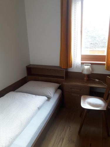 1 dormitorio con 1 cama, 1 silla y 1 ventana en Posterhof, en Valdaora