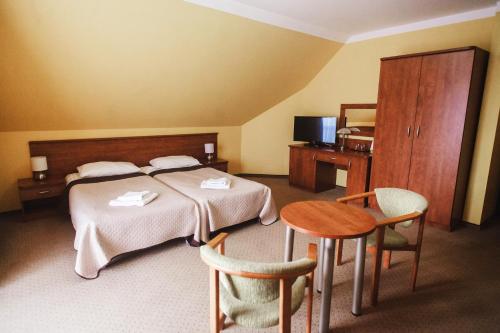 pokój hotelowy z łóżkiem, stołem i krzesłami w obiekcie DW Airen w Trzęsaczu