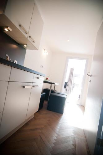 a kitchen with white cabinets and a wooden floor at Apartment De Maasnacht in Maaseik