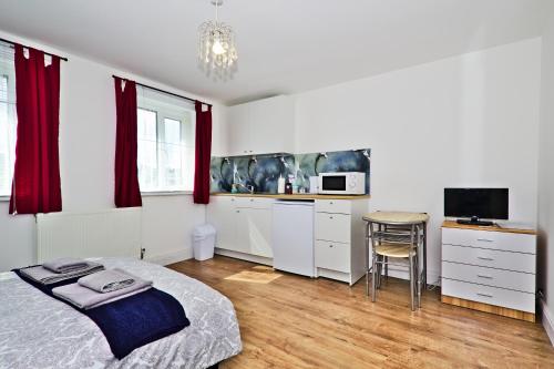 a bedroom with a bed and a desk and a kitchen at Harlinger Lodge in London