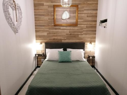 a bedroom with a green bed with a wooden wall at Cantinho do Ilhéu in Ponta Delgada