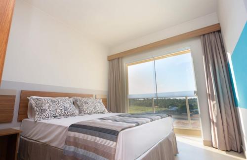 a bedroom with a bed and a large window at Ilhas do Lago Eco Resort in Caldas Novas