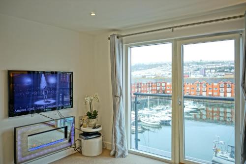 a room with a large window with a view of a marina at Soak up the Light at a Soothing, Stylish Apartment in Swansea Marina in Swansea