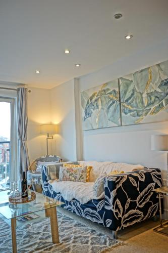a living room with a couch and a painting on the wall at Soak up the Light at a Soothing, Stylish Apartment in Swansea Marina in Swansea