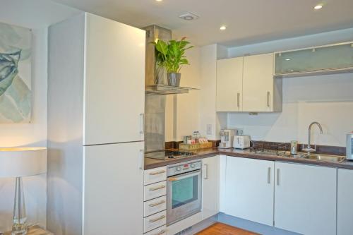 a kitchen with white cabinets and a white refrigerator at Soak up the Light at a Soothing, Stylish Apartment in Swansea Marina in Swansea