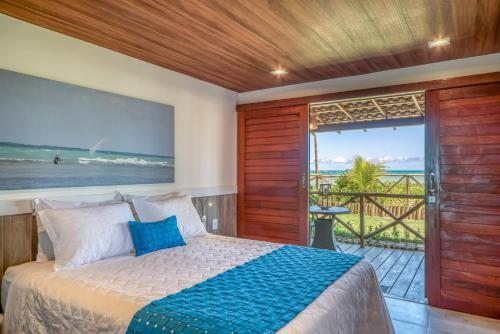 a bedroom with a bed and a balcony with the ocean at Wassu Pousada in São Miguel dos Milagres