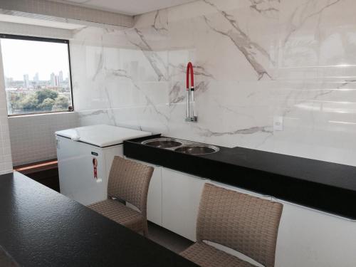a kitchen with white marble walls and a counter with chairs at Manaíra Apart Hotel in João Pessoa
