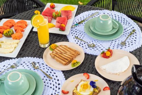 a table with plates of breakfast food on it at Wassu Pousada in São Miguel dos Milagres